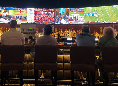 a group of people sitting at a bar watching the games