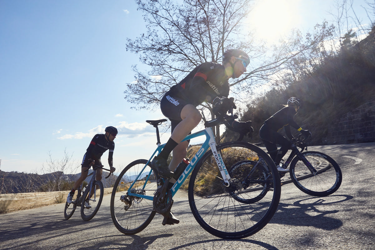 a group of cyclists climbing up the road with blue sky behind them