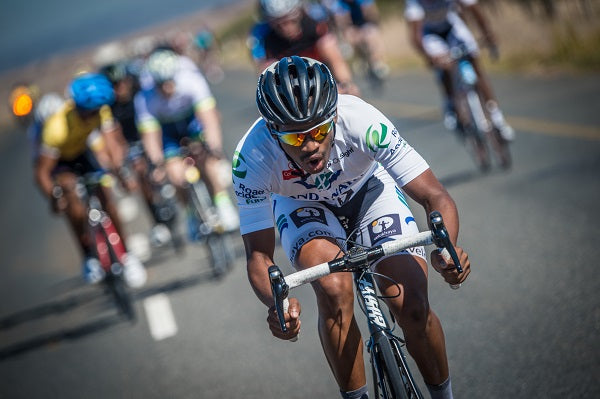 a cyclist in white kit sprinting away from a group of cyclists in a race