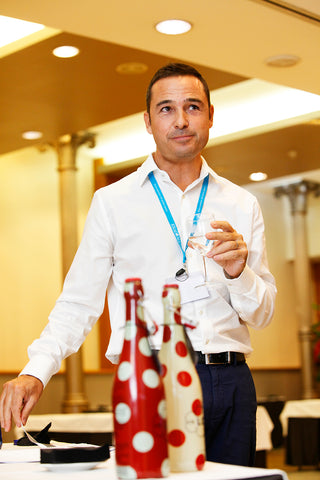 Bruno Balbas, CEO of Lolea Sangria with white and red polka dot sangria bottles in front of him