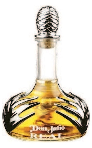 Wide bottomed Don Julio Real Tequila bottle with silver agave leaf design and thin bottleneck topped with silver pina cork, filled with golden extra anejo tequila liquid.