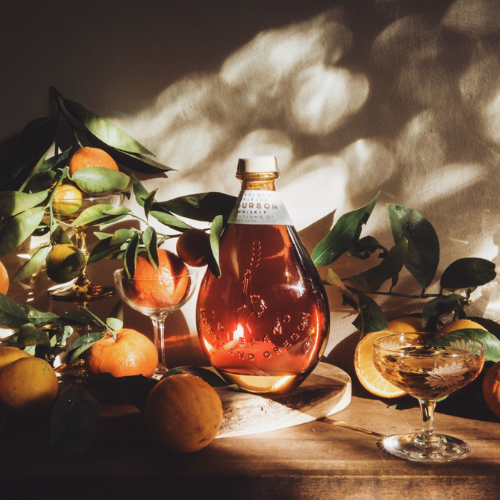 freeland spirits bourbon bottle on a table with a glass and oranges nearby