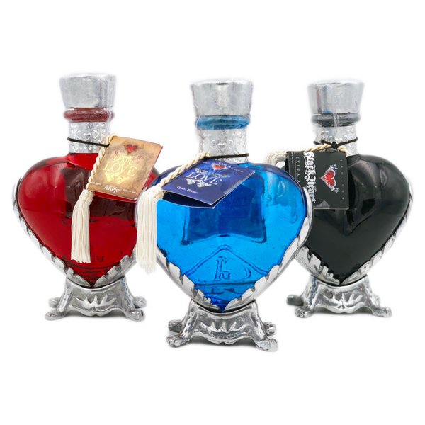 Three heart shaped bottles of Grand Love Tequila, one blue, one red, one black, with silver stand, lining, and short neck.