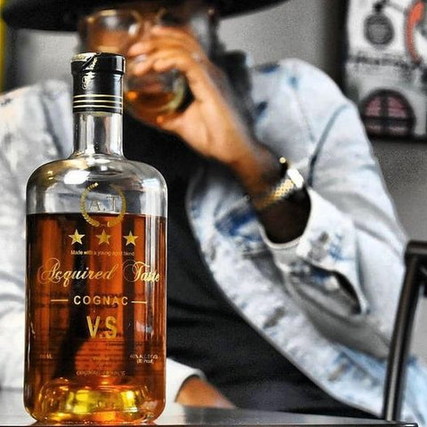 charles mingo, founder of acquire taste cognac sipping cognac with a bottle of acquire taste cognac vsop in front of him