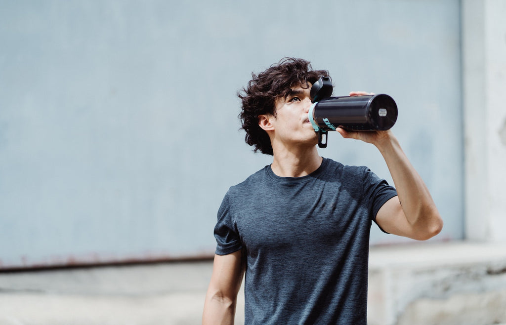 Young athletic man drinking water from reusable bottle