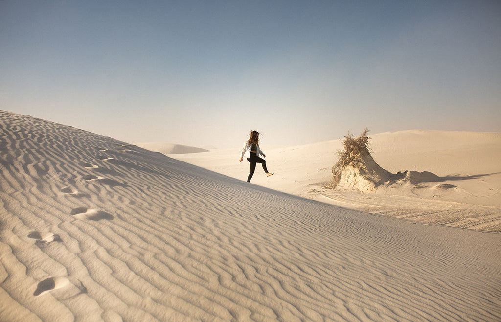 Woman walking along a desert sand dune