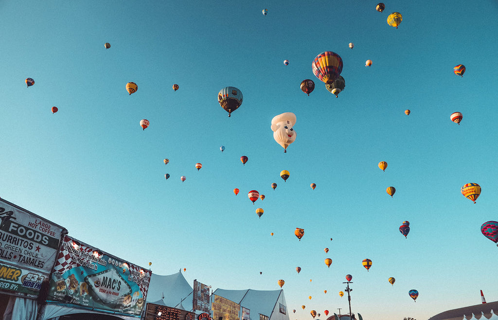 Many hot air balloons flying above a festival