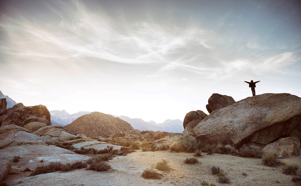 Person atop rock with arms outstretched