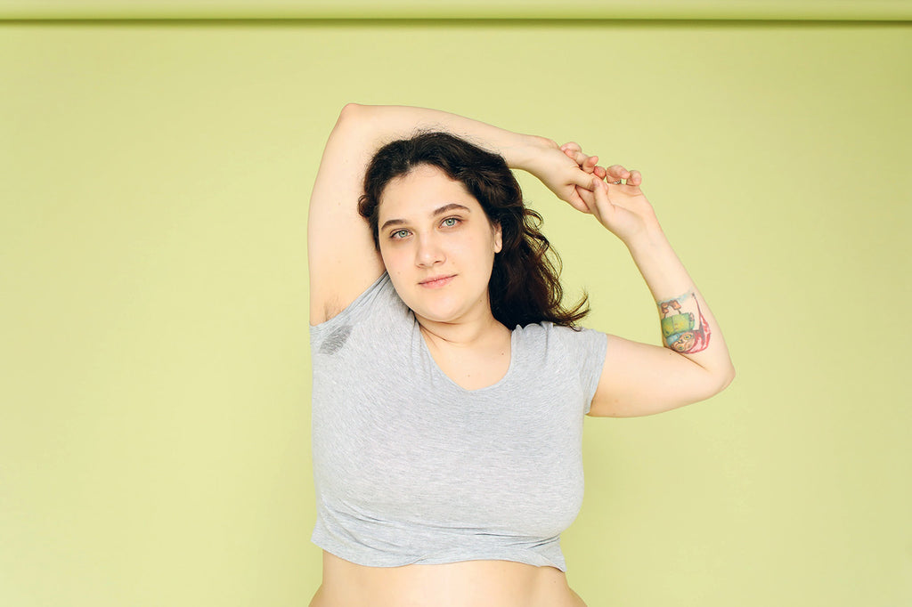 Woman in front of green background with armpit stain