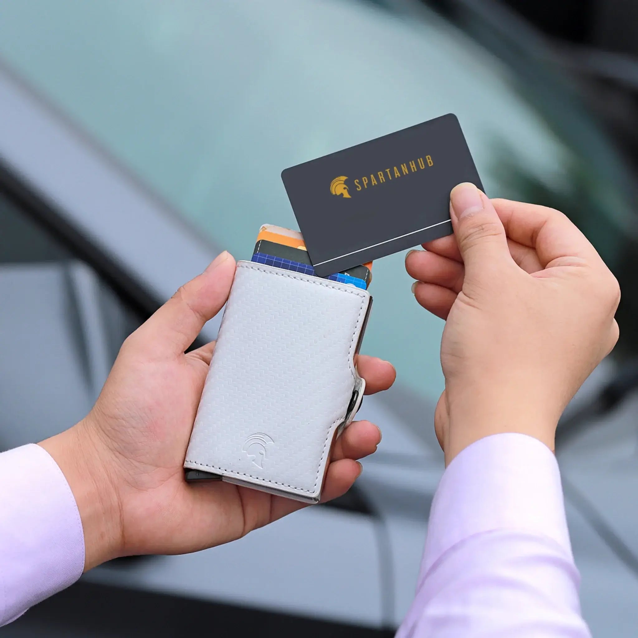 SPARTANHUB Smart Wallet – RFID-geschütztes Portemonnaie in weisser Carbon-Optik mit Pop-up-Kartenfunktion, fotografiert im Freien.