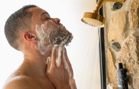 Man shampooing and conditioning beard in shower