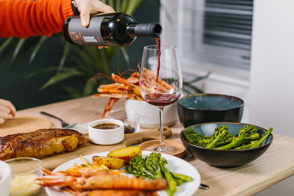 a table of food with wine, langoustines and steak 