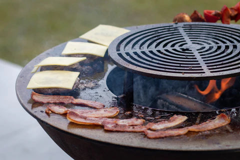 bacon and cheese burgers cooking on an outdoor grill