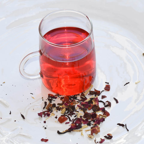 wellness tea in a clear glass cup with tea leaves on a plate