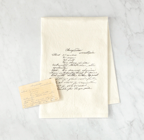 printed natural recipe tea towel laying on gray marble table 