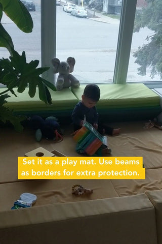 baby sitting on bases playing with toys independently near a window