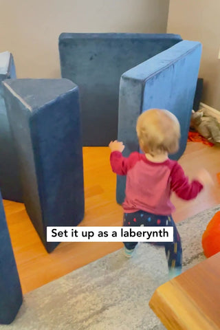 baby walking towards a labyrinth made out of foam cushions