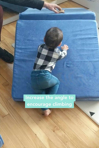 baby developing gross motor skills by climbing on a play couch to reach a toy