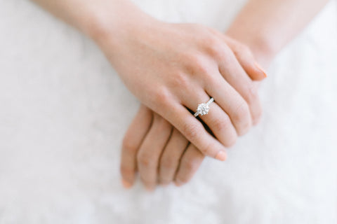 close up of brides clasped hands with diamond engagement ring on finger