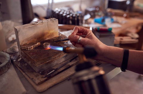 Close up of jewllery working on ring with blow torch