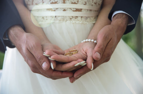 Just Gold Jewellery - two golden wedding rings on bride and groom s palm