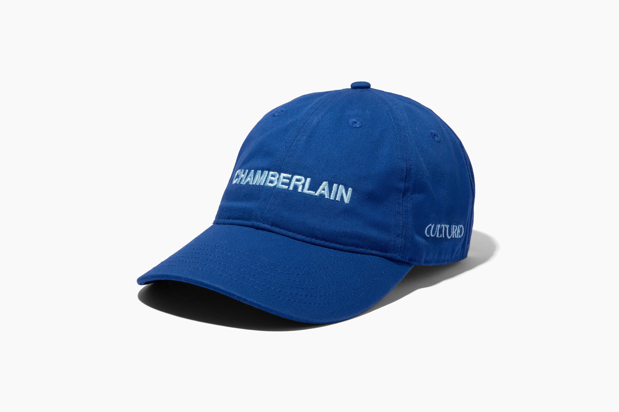 Royal blue baseball cap with "CHAMBERLAIN" embroidered in white on the front, minimalist unisex hat on white background from Cultured Magazine Hamptons Issue.