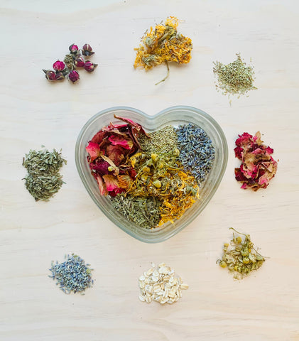 Small piles of colorful herbs arranged around a heart-shaped dish filled with these herbs