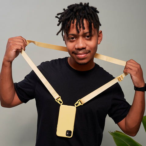 Modelo negro sorrindo com camiseta preta e capinha amarela com alça pendurada no pescoço