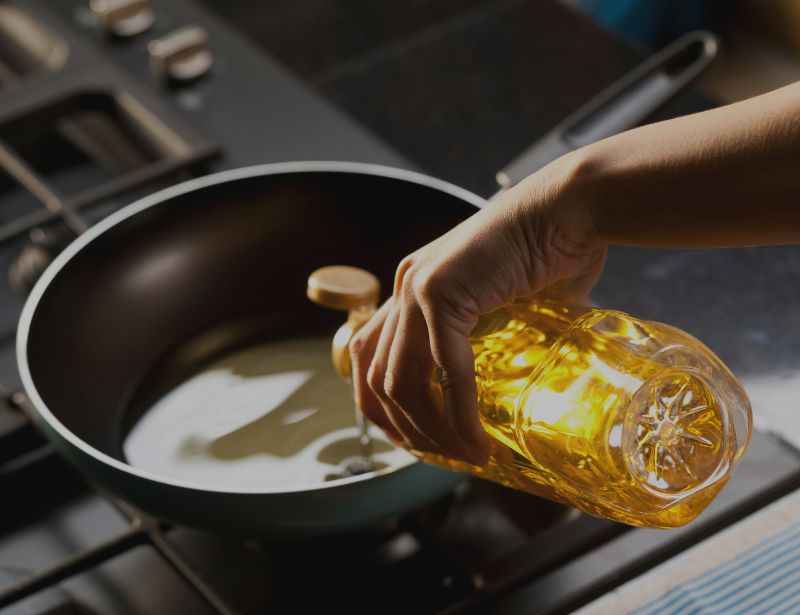 Hand pouring oil on a pan