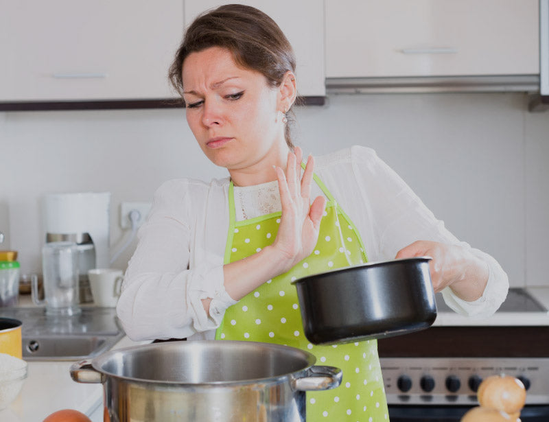 Woman in dotted green apron pushing away smelly pot