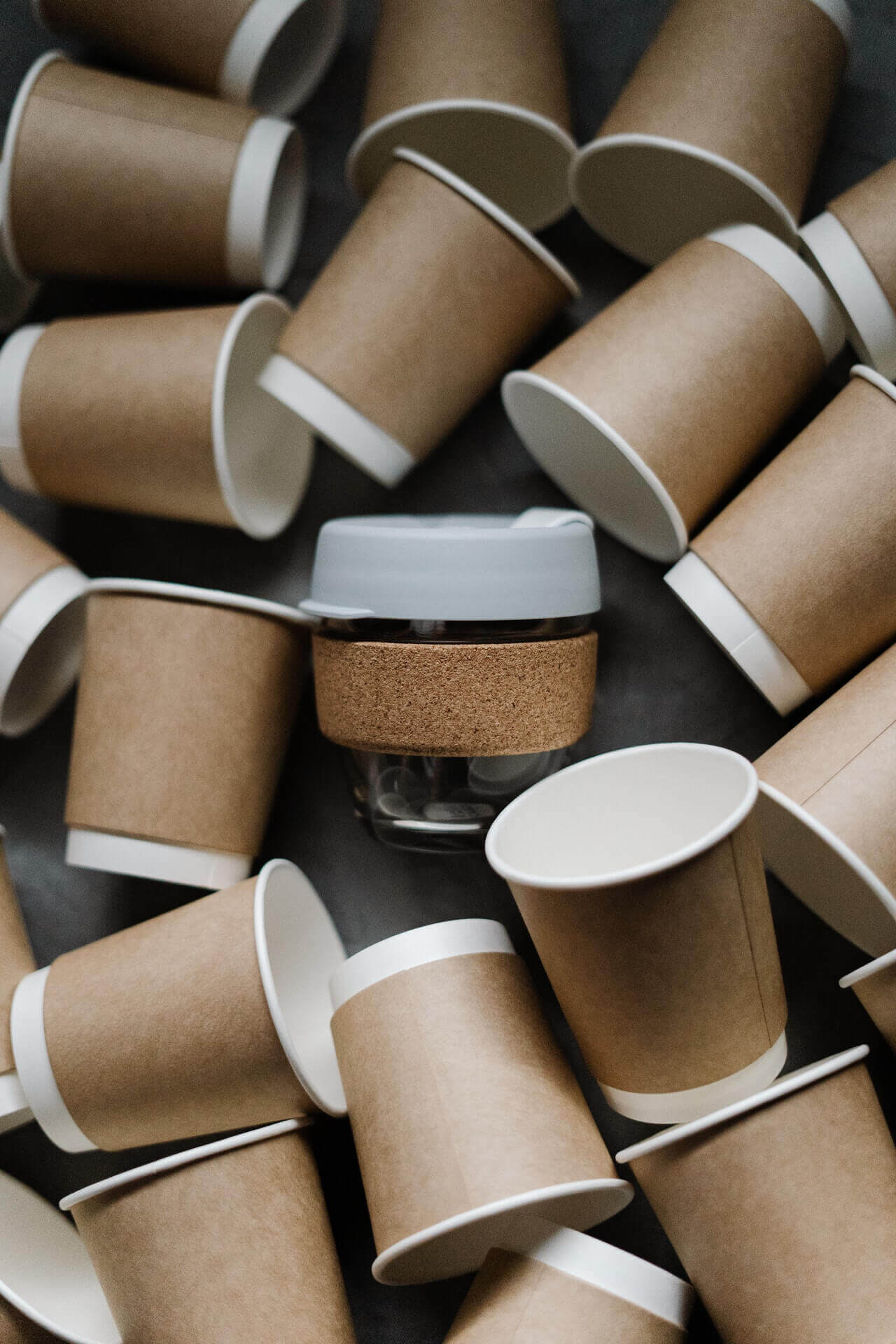 Reusable coffee cup surrounded by paper coffee cups