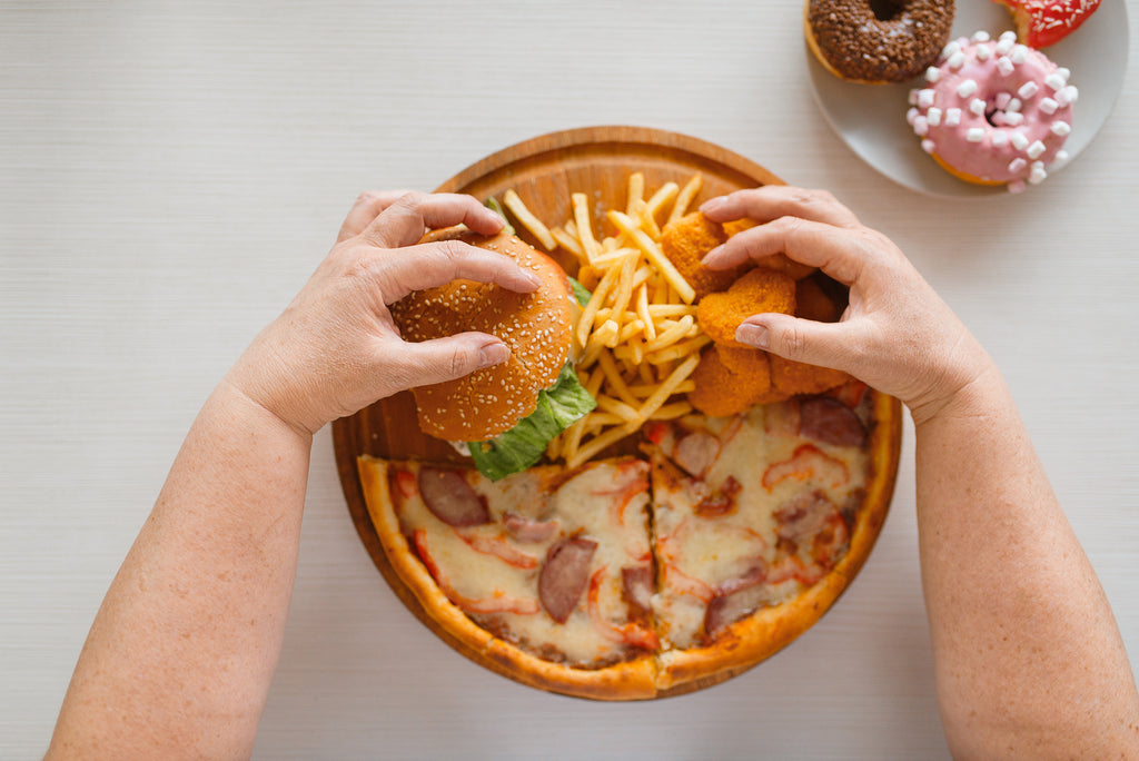 ピザとハンバーガーとフライドポテトとチキンナゲットをたべる肥満の人