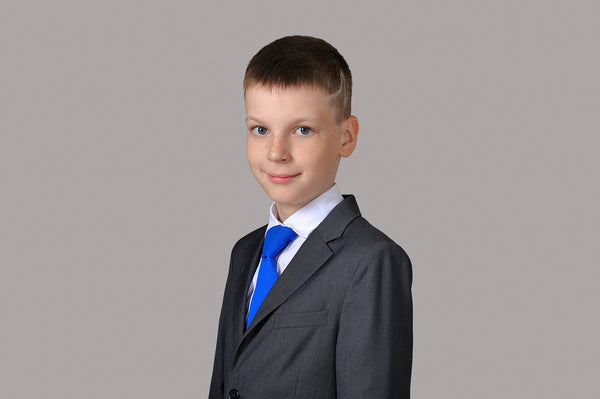 Photo of a young boy dressed in a sharp tuxedo, perfect for formal occasions and boys' tuxedo attire