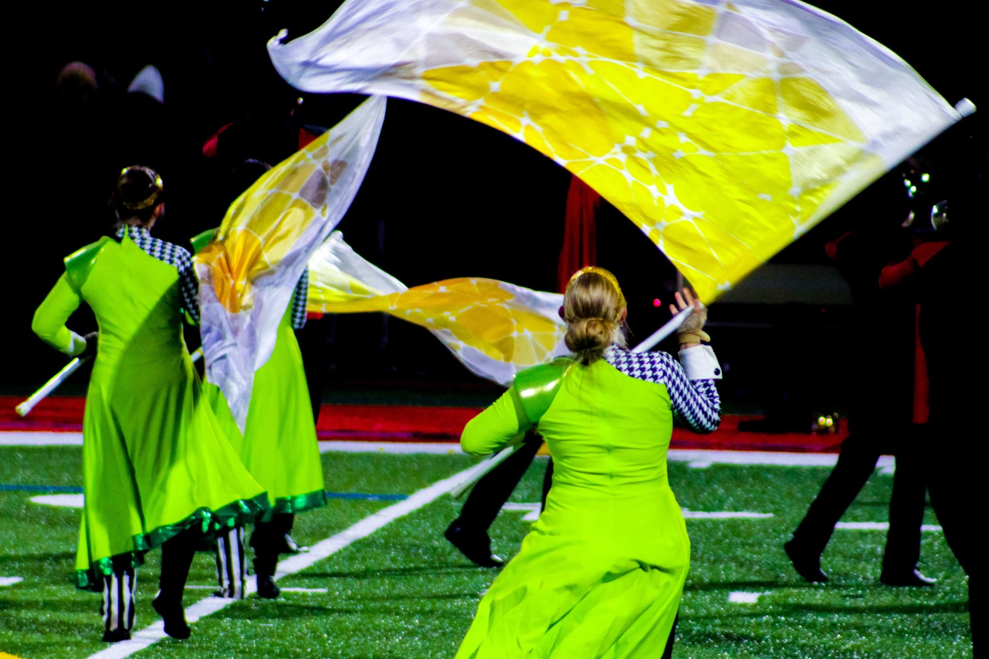 Colorful marching band flags waving in the air during a performance, adding vibrant energy to the event. Ideal for marching band enthusiasts and performers seeking dynamic visuals
