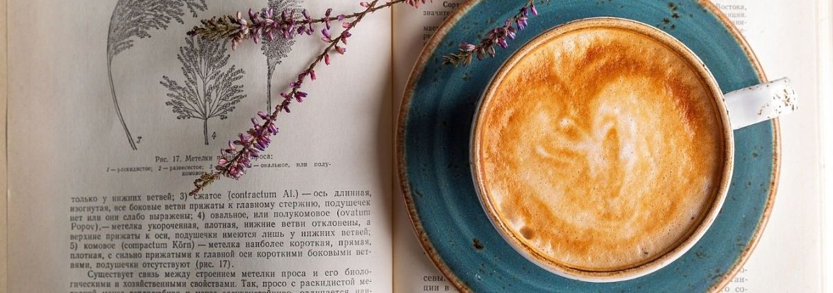 Imagen de taza de café con leche sobre libro de botánica