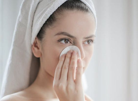 woman cleaning her face with facial wipes