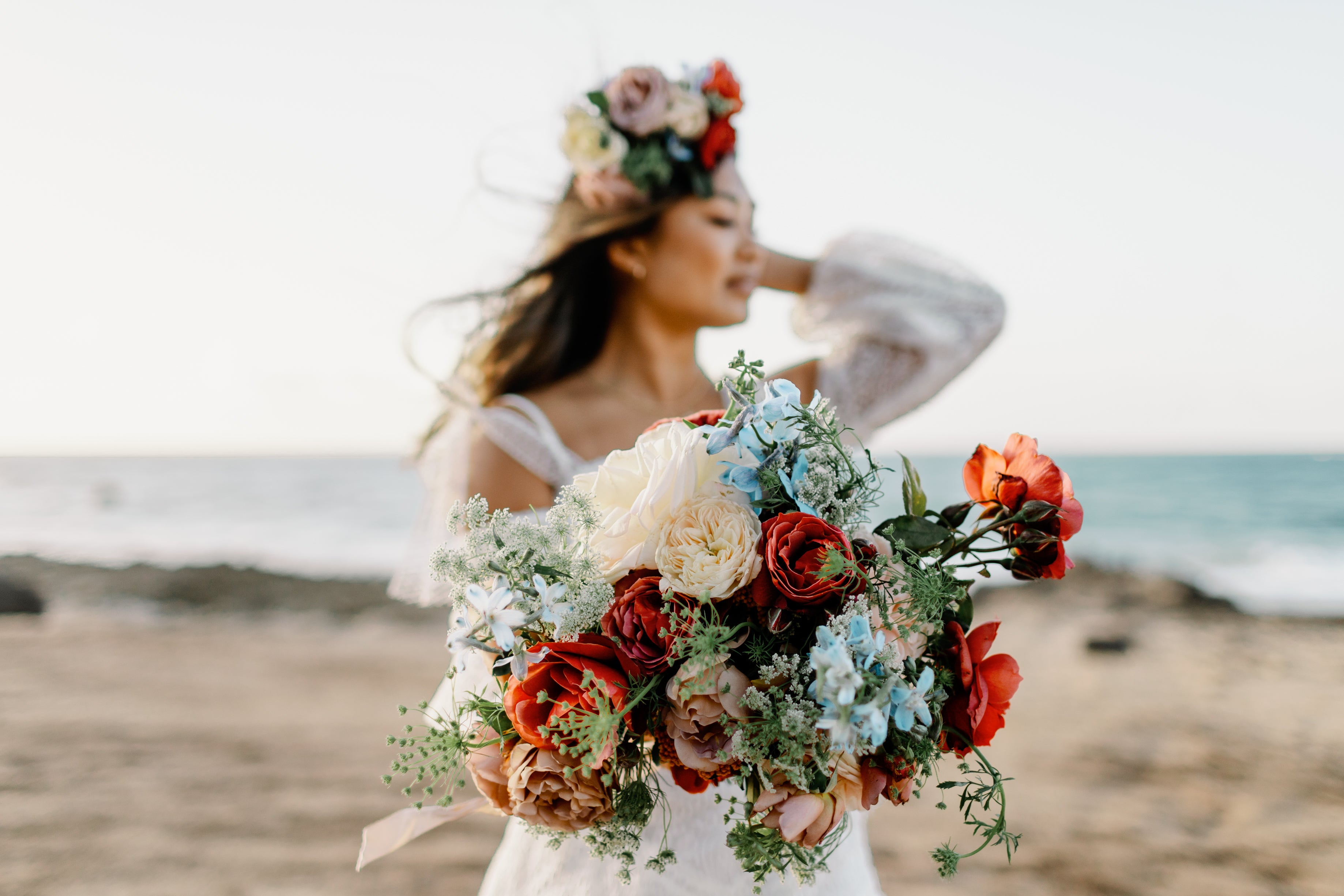 Model wearing heirloom rose headpiece and carrying a garden rose bouquet on the beach