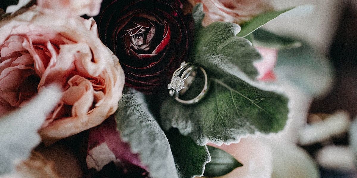 Wedding rings nestled in a pink and red bridal bouquet