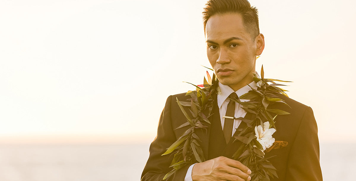Close-up of a young man wearing a Maile ti-leaf lei and white orchid boutonniere