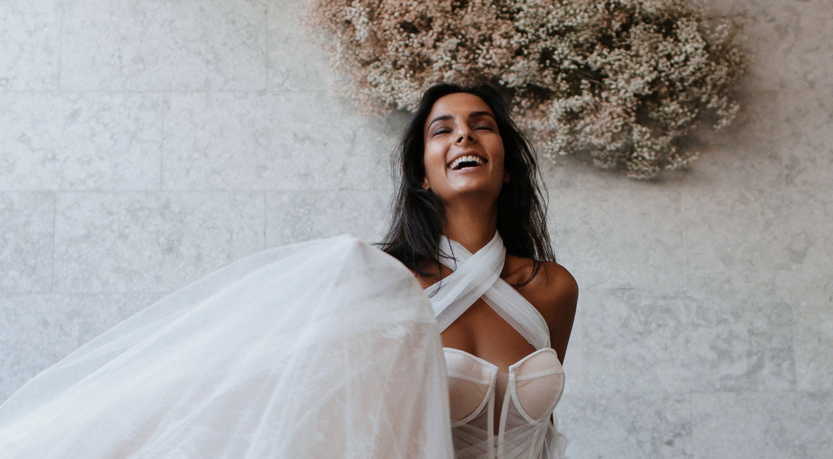 Closeup of bridal model wearing a bustier dress, laughing, with a flower cloud behind her