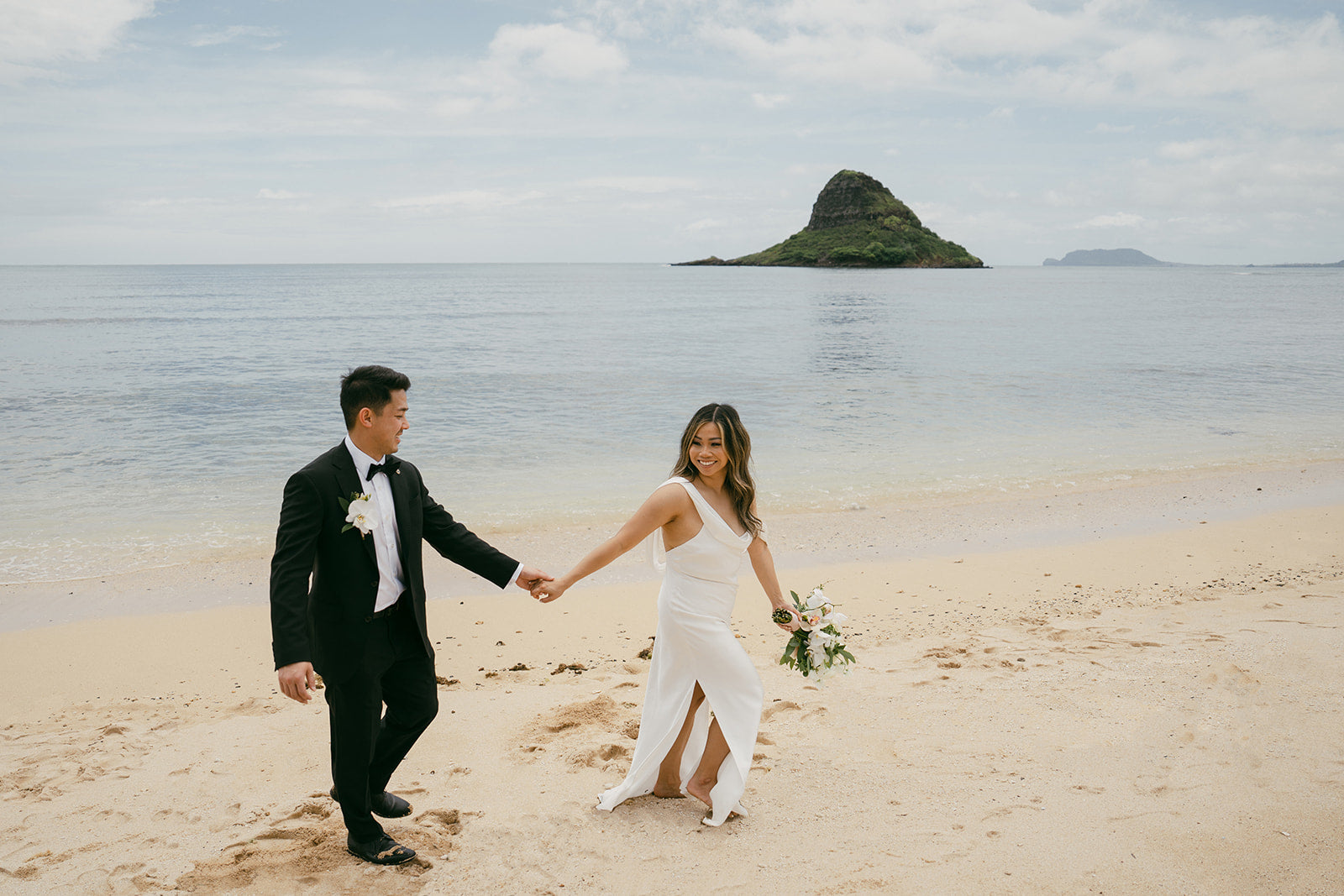 A couple eloping on the beaches of Oahu in front of China Man's Hat by Masha Sakhno Photo