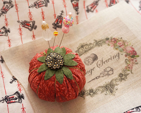 Tomato pincushion made with yo-yo quilt and vintage buttons