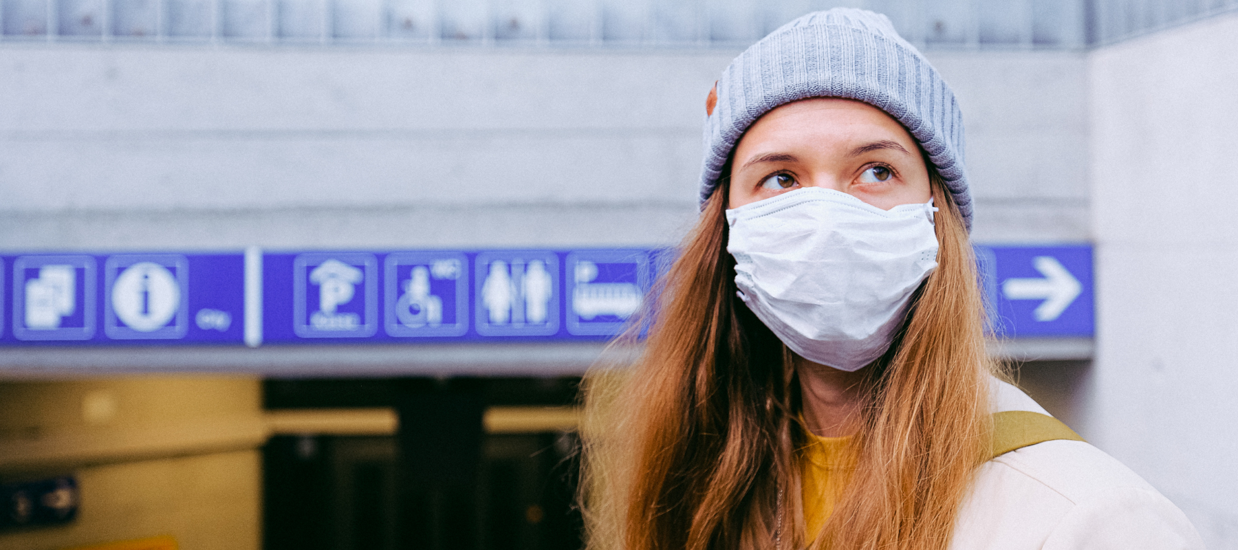 woman suffering from migraine wearing mask in front of hospital