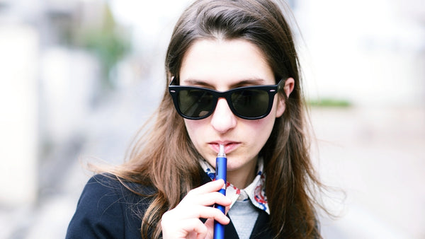 woman wearing sunglasses vaping 