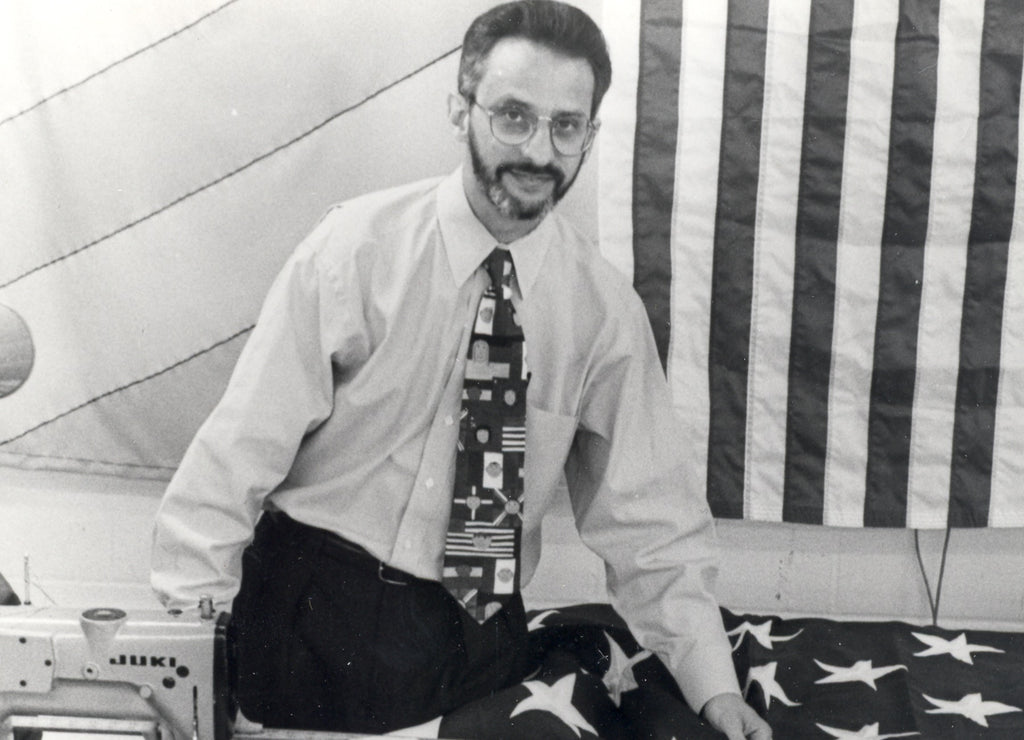 Ron Kronberg with sewing machine and American flag in black and white