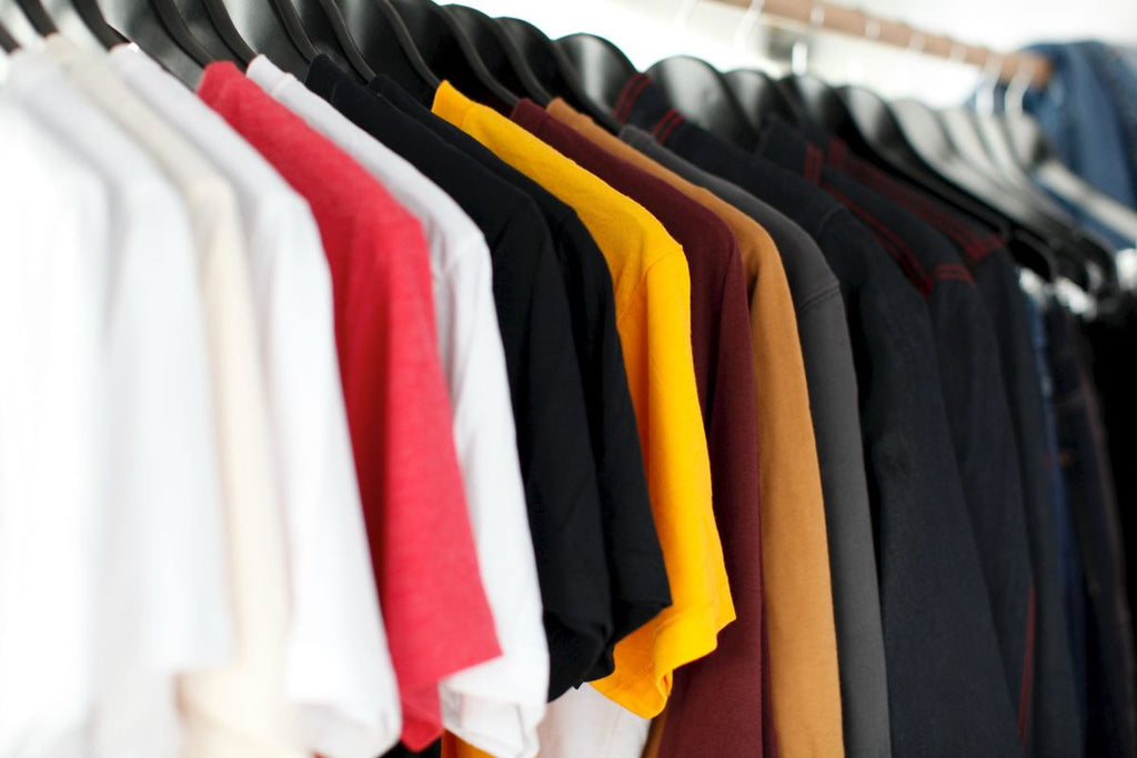 A clothing rack of several plain black, red, yellow, and brown shirts.