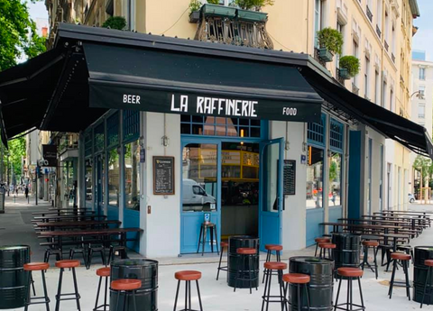 Une image contenant plein air, bâtiment, tables, chaises de bar