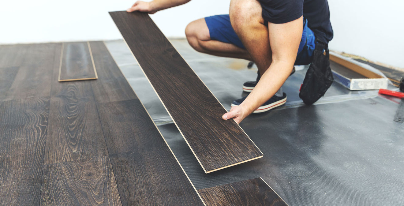 A worker installing click-lock flooring