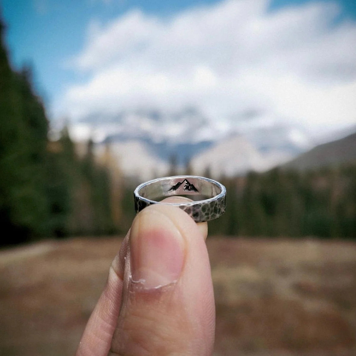 Silver ring with mountain stamp detail, photographed against the backdrop of Mount Robson in Canada