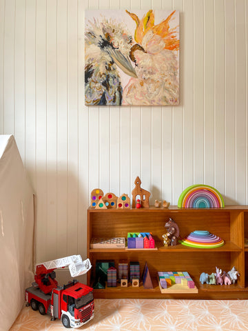 Square canvas kookaburra cockatoo art print above toys in play room.